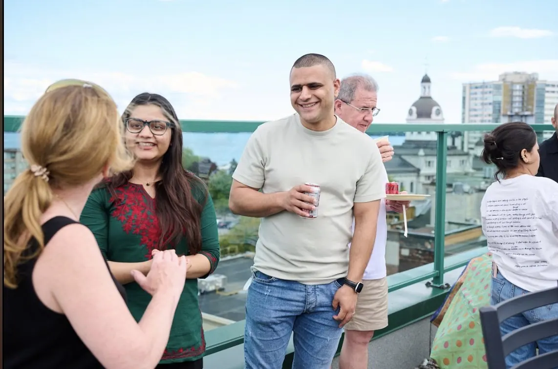 Adnan chatting with other attendees on a rooftop terrace in downtown Kingston