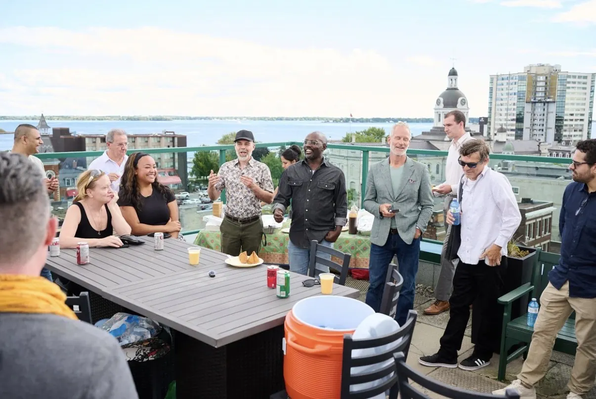 A group gathered on a rooftop terrace overlooking Kingston City Hall and the lake